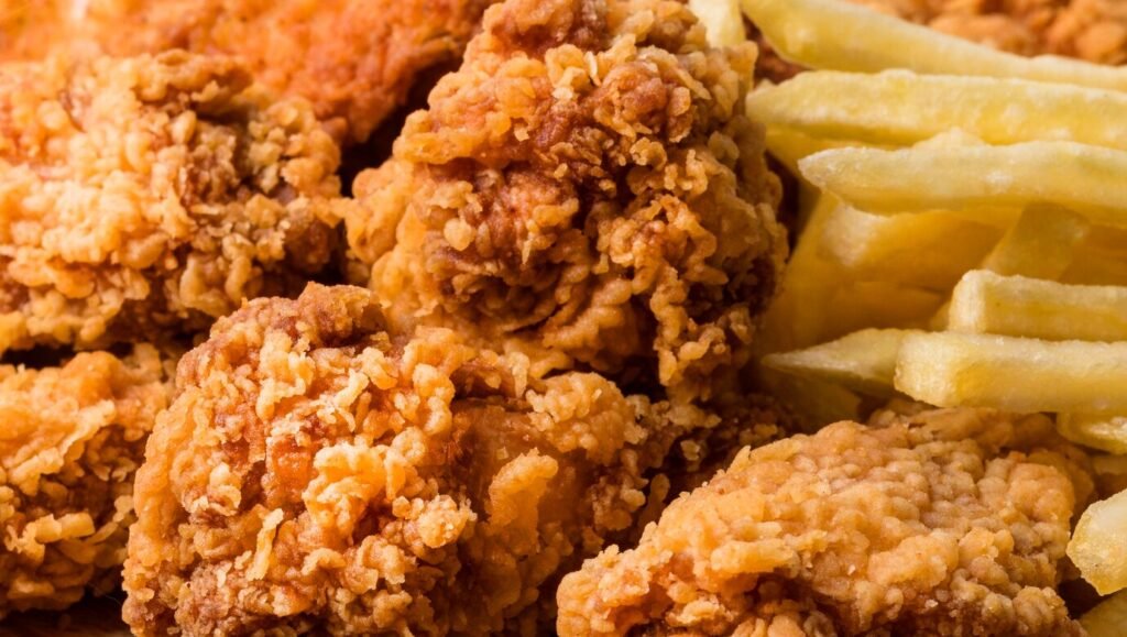 Close-up of crispy fried chicken wings served with golden fries