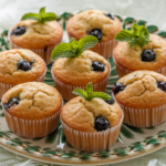 Mini banana muffins with blueberries baked inside, served on a decorative plate.