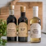 Three types of balsamic vinegar: traditional DOP, IGP, and white balsamic vinegar in distinct bottles.